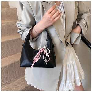 Détail du sac à main noir en cuir PU avec charm en perles et accessoire nœud à carreaux