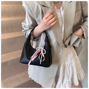 Détail du sac à main en cuir noir avec perles élégantes et nœud en ruban rose
