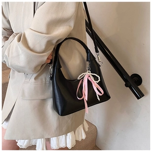 Détail du sac demi-lune en cuir noir avec nœud en perles et ruban à carreaux