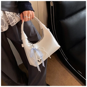 Détail du sac blanc en cuir PU avec chaîne de perles et pendentif nœud à carreaux