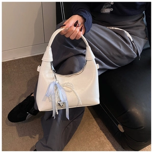 Détail du sac à main blanc demi-lune avec nœud à carreaux bleus et breloque perle