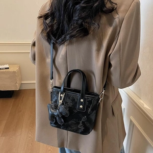 Petit sac seau chic en cuir noir avec breloque chiot et détails gaufrés pour femme