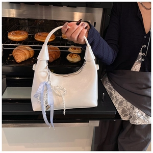 Detail of white glossy oil wax leather handbag with pearl chain and bow accessory