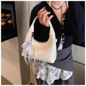Détail d'un sac à main blanc avec pendentif perle et ruban à carreaux bleu décoratif