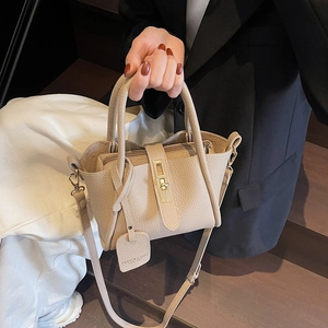 Elegant beige lychee grain leather bucket bag with gold twist lock and adjustable strap