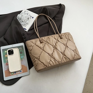Detail of quilted puffy tote bag in beige with large diamond stitching and soft texture
