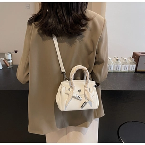 Dettaglio borsa a mano bianca in pelle con chiusura argento e foulard in seta su manico