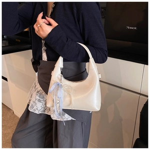 Détail du sac à main blanc en demi-lune avec nœud en perles et ruban de soie élégant