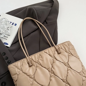 Close-up of beige quilted tote bag showing soft cloud stitching on grey fabric background