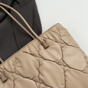 Detail of khaki quilted tote bag featuring soft diamond stitching and cord shoulder straps