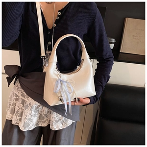 Detailed view of white crescent handbag with pearl pendant and blue plaid bow accessory