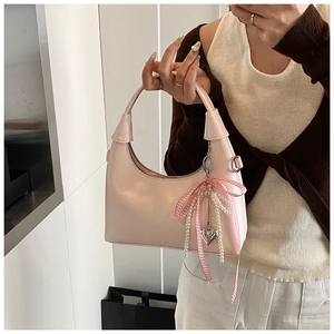 Vue détaillée du sac à main rose pâle avec breloques de perles et nœud décoratif