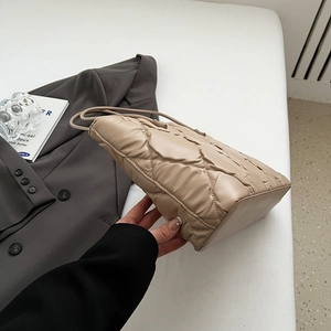Detailed side view of beige quilted bubble tote bag showing soft texture and capacity