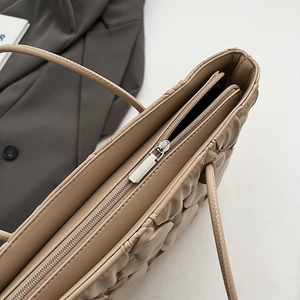Close-up of silver zipper closure and quilted texture on khaki tote bag