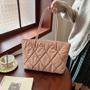 Close-up of quilted puffy tote bag in satin pink finish on a cozy lifestyle background