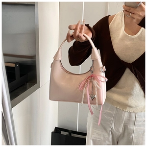 Détail du sac demi-lune rose avec nœud, chaînes de perles et pendentif cœur argenté