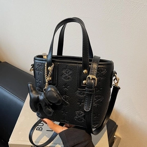 Black embossed leather bucket bag with star patterns, gold hardware, and puppy charm