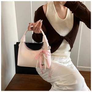 Détail du sac carré rose avec chaîne en perles, nœud ruban et pendentif en cœur