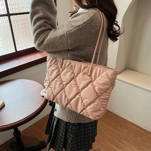 Detail of pink quilted puffer tote bag featuring rhombic stitching and leather-look straps