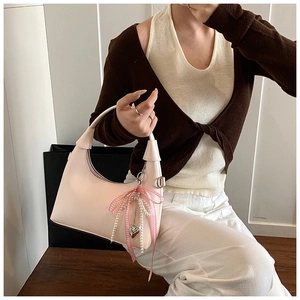 Detail of light pink semi-circle handbag with plaid bow and pearl heart charms