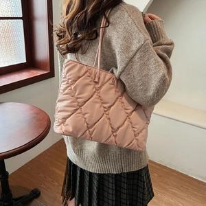Detail of pink quilted tote bag with diamond stitching shown in a lifestyle indoor setting