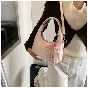 Détail du sac lune rose clair avec perles et nœud porté par un mannequin en mode