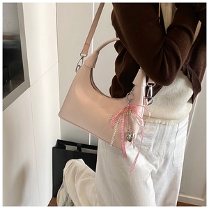 Detail of pink shoulder bag with ribbon bow, pearl tassel and heart pendant charm
