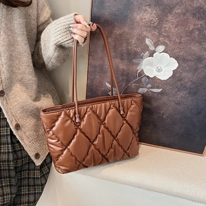 Detail of coffee brown quilted tote bag showing diamond stitching and long handles