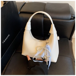 Détail du sac à main en cuir blanc avec nœud en perles et ruban à carreaux bleus