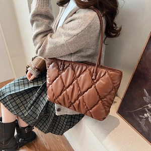 Detail of a brown quilted puffer tote bag featuring a glossy finish and chic rhombic pattern