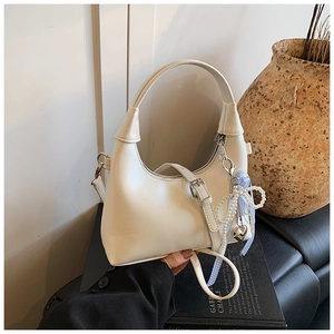 Détail du sac bandoulière demi-lune crème avec perles et ruban bleu décoratif