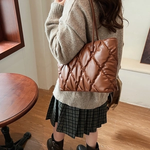 Detail of dark brown quilted puffer tote bag with glossy finish and rhombus stitching