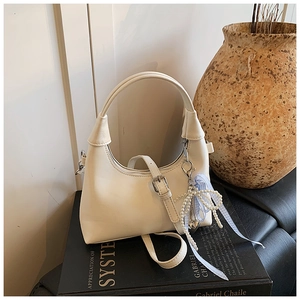 Détail du sac hobo blanc cassé avec pendentif nœud perlé et ruban bleu à carreaux