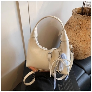 Détail du sac hobo avec breloque nœud en perles et ruban à carreaux bleu sur cuir