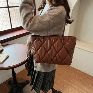 Detailed view of brown quilted tote bag with diamond stitching and soft leather texture