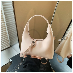 Détail d'un sac à main beige en similicuir avec poignée incurvée et bandoulière réglable