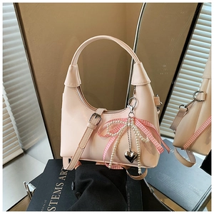 Détail du sac à main rose poudré en simili cuir avec nœud perlé et pendentif cœur