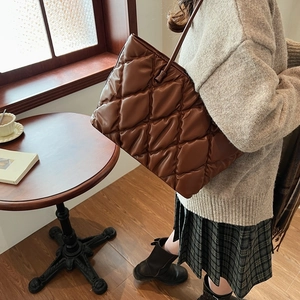 Macro detail of dark brown quilted tote bag with soft leather texture and stitch pattern