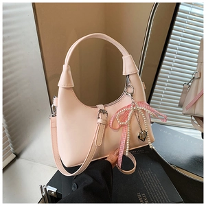 Détail du sac à main en cuir rose avec breloque nœud perlé et bandoulière réglable