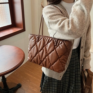Brown quilted tote bag in soft PU leather worn by a model in a cozy vintage setting