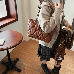 Macro detail of caramel brown quilted tote bag with soft PU leather stitching texture