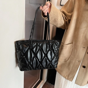 Close-up of a glossy quilted tote bag with diamond stitching and slim handles