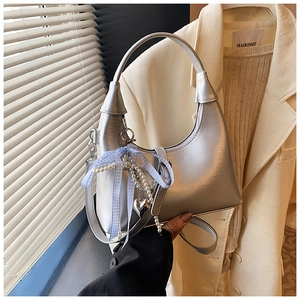 Détail du sac à main argenté métallisé avec nœud à carreaux bleus et breloques perles