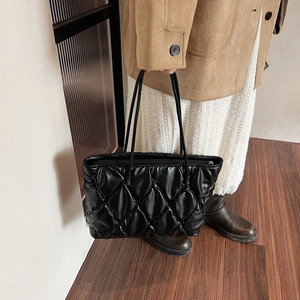 Close-up of quilted black puffer tote bag with elegant diamond stitching and slim straps