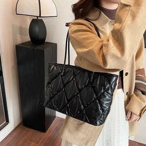 Detail of black quilted puffer tote bag showing soft leather texture and stitch patterns