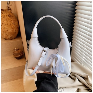 Détail du sac à bandoulière bleu clair avec pendentif perle dans un décor chaleureux