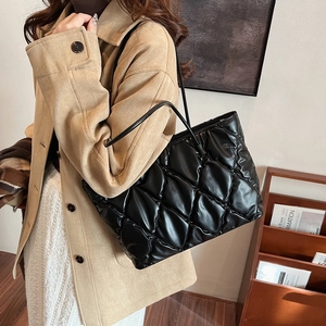 Close-up of black quilted tote bag featuring a high-gloss finish and puffy texture