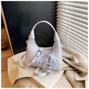 Détail du sac bandoulière bleu clair avec nœud ruban, perles et pendentif cœur