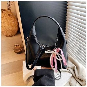 Détail du sac demi-lune en cuir noir avec breloque nœud en perles et ruban rose