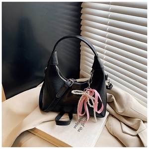 Détail d'un sac à main en cuir noir avec perles et nœud à carreaux roses élégant
